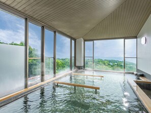 A modern indoor pool with large windows offering views of a lush landscape. - Wan Wan Paradise Premier Izukogen (Ito)