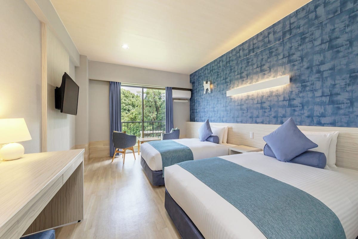 Une chambre d’hôtel moderne avec deux lits, un bureau et une télévision.