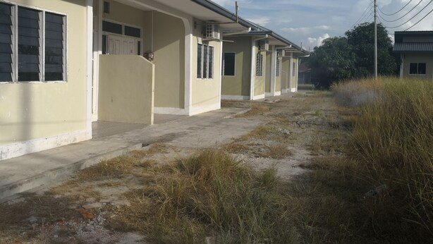 A row of single-story buildings with a flat roof, a concrete pathway, and a grassy area in front. - Kuala Mengalong Cottage (Sipitang)