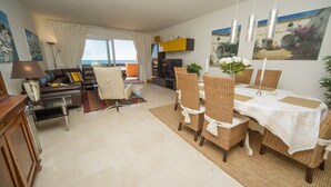 Uma sala de estar moderna com um sofá, uma mesa de jantar com cadeiras e uma televisão.