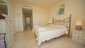 A hotel room with a bed, bedside table, lamp, and a painting on the wall.