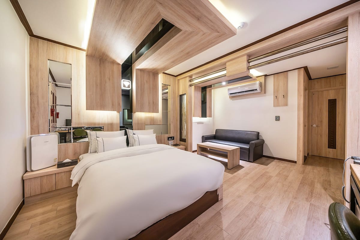 Ein modernes Hotelzimmer mit einem großen Bett, einem Schreibtisch, einer Couch und einem Spiegel.