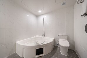 Un baño con bañera independiente, inodoro y cabezal de ducha.