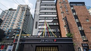 Hotel JW com fachada moderna, vários andares e uma entrada imponente com toldo preto.