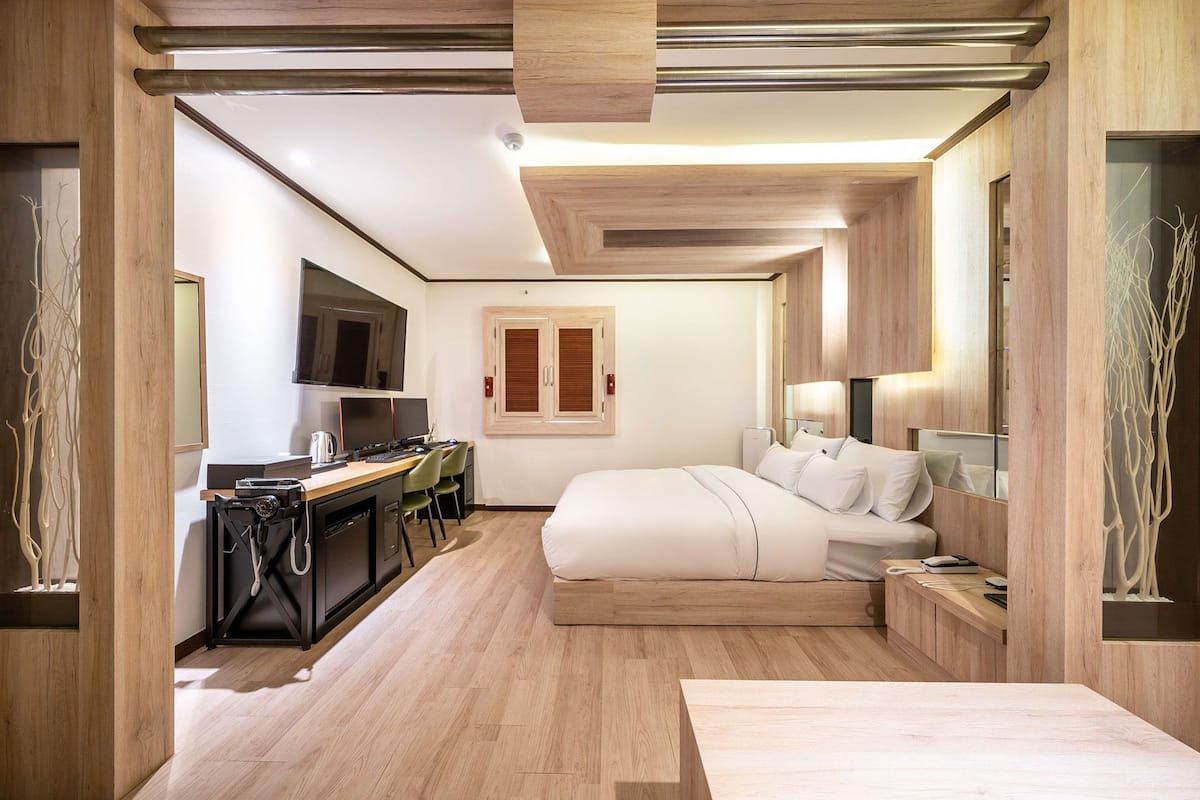 Ein modernes Hotelzimmer mit Bett, Nachttisch, Schreibtisch und Stuhl.