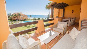 A balcony with outdoor furniture, a pool, and a view of the sea and buildings. - Los Granados de la Duquesa 421 (Manilva)