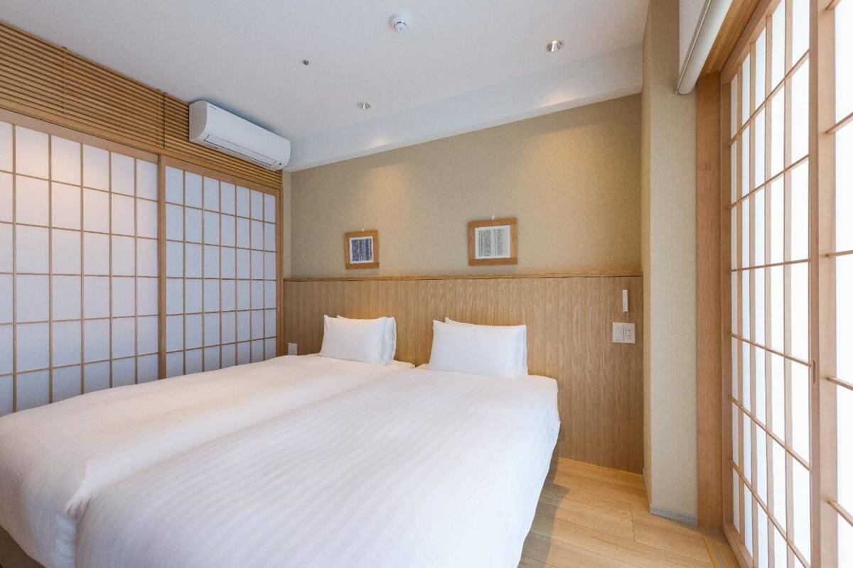 A hotel room with a large bed, wooden headboard, and sliding shoji screens.