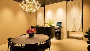 A conference room with a round table, chairs, a chandelier, a reception desk with a monitor, and a plant. - 9 Hotel Hakata (Fukuoka)
