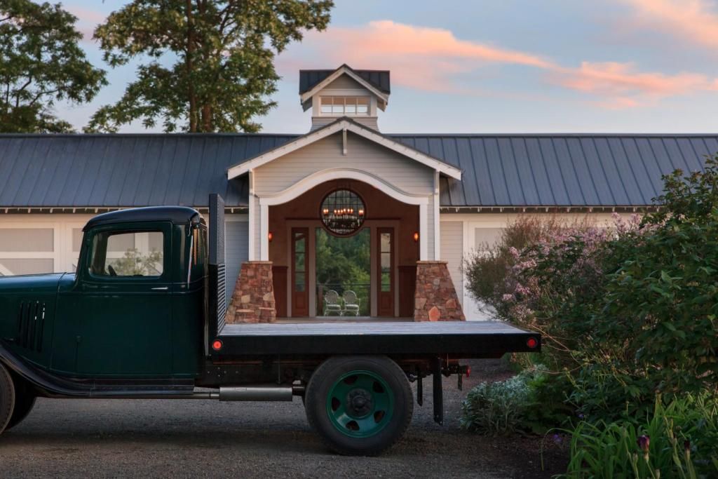 Un camion vert d’époque est garé devant un bâtiment doté d’un toit en métal et d’un porche.