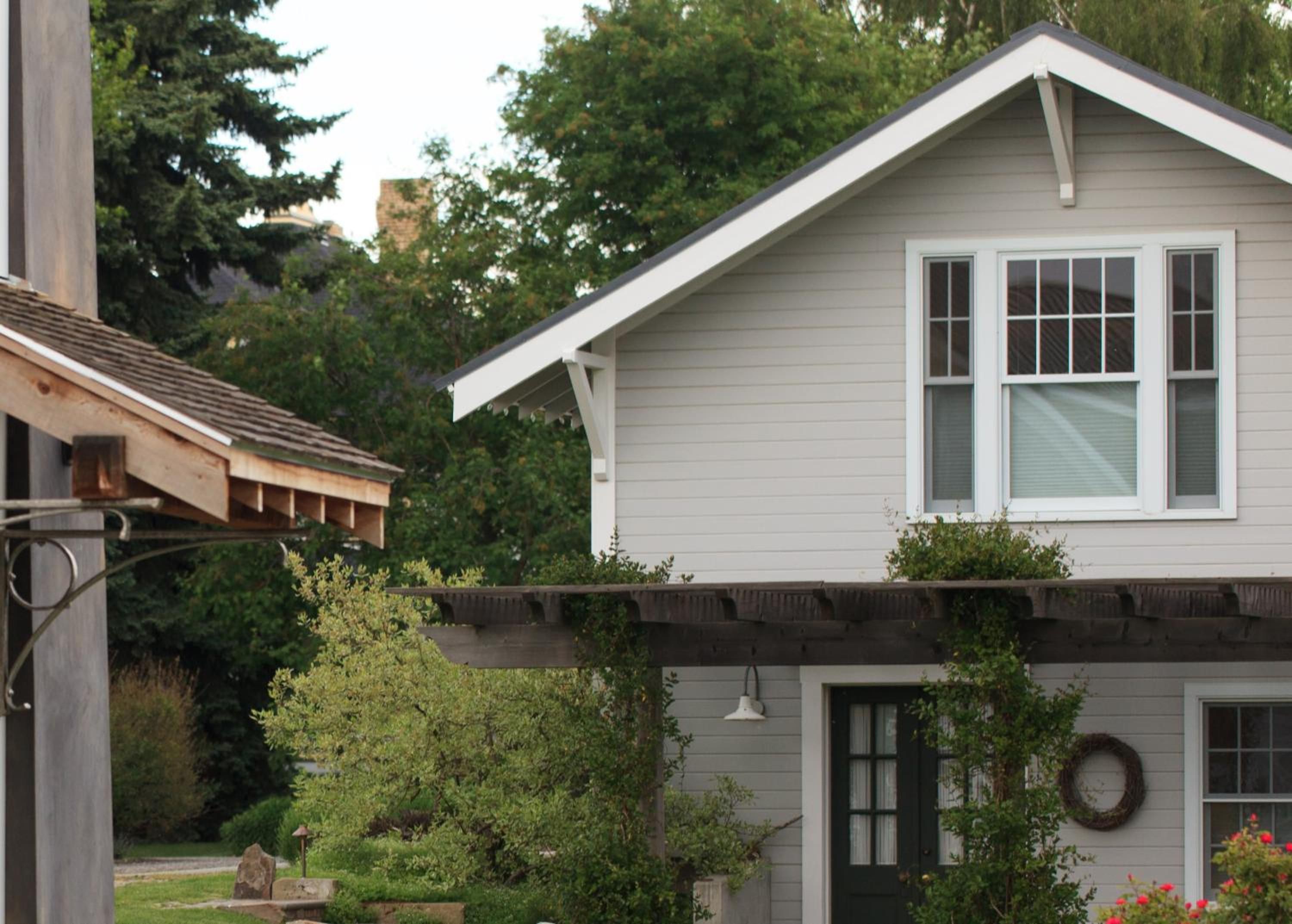 A residential house with a gabled roof, a front porch with a railing, and a front door with a wreath.