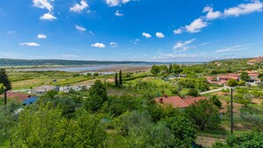 Paesaggio rurale con case, vegetazione e un fiume.