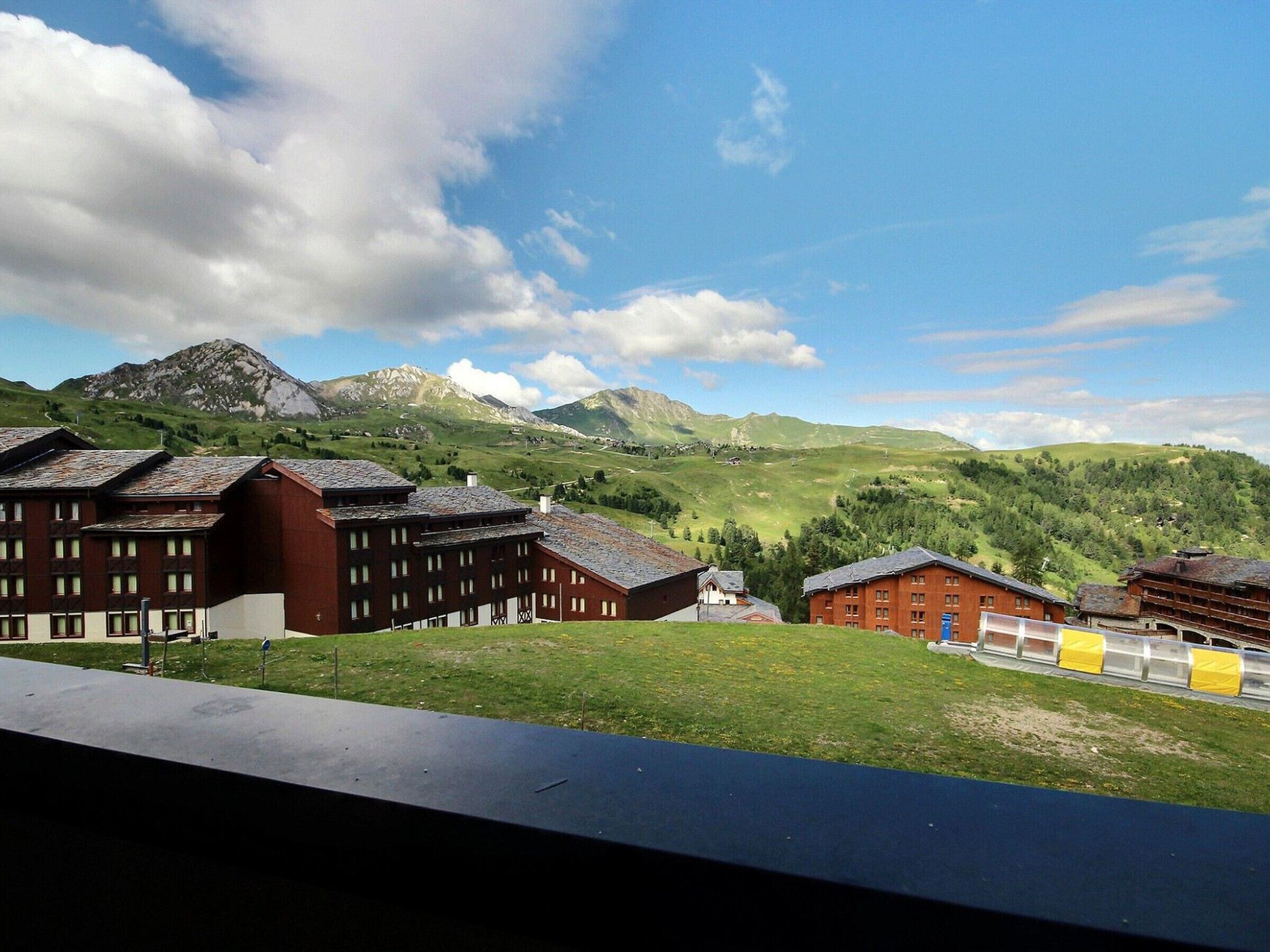 A hotel with multiple buildings, a grassy area, and a mountainous backdrop.