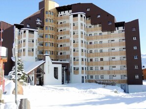 Hotel features a modern design with dark and light paneling, multiple balconies, and a covered entrance.