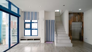 Ein modernes Interieur mit einer Treppe, einer eingebauten Bank und einem großen Fenster mit Jalousien.