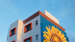 Ein Gebäude mit einem großen Wandgemälde von einer Sonnenblume.