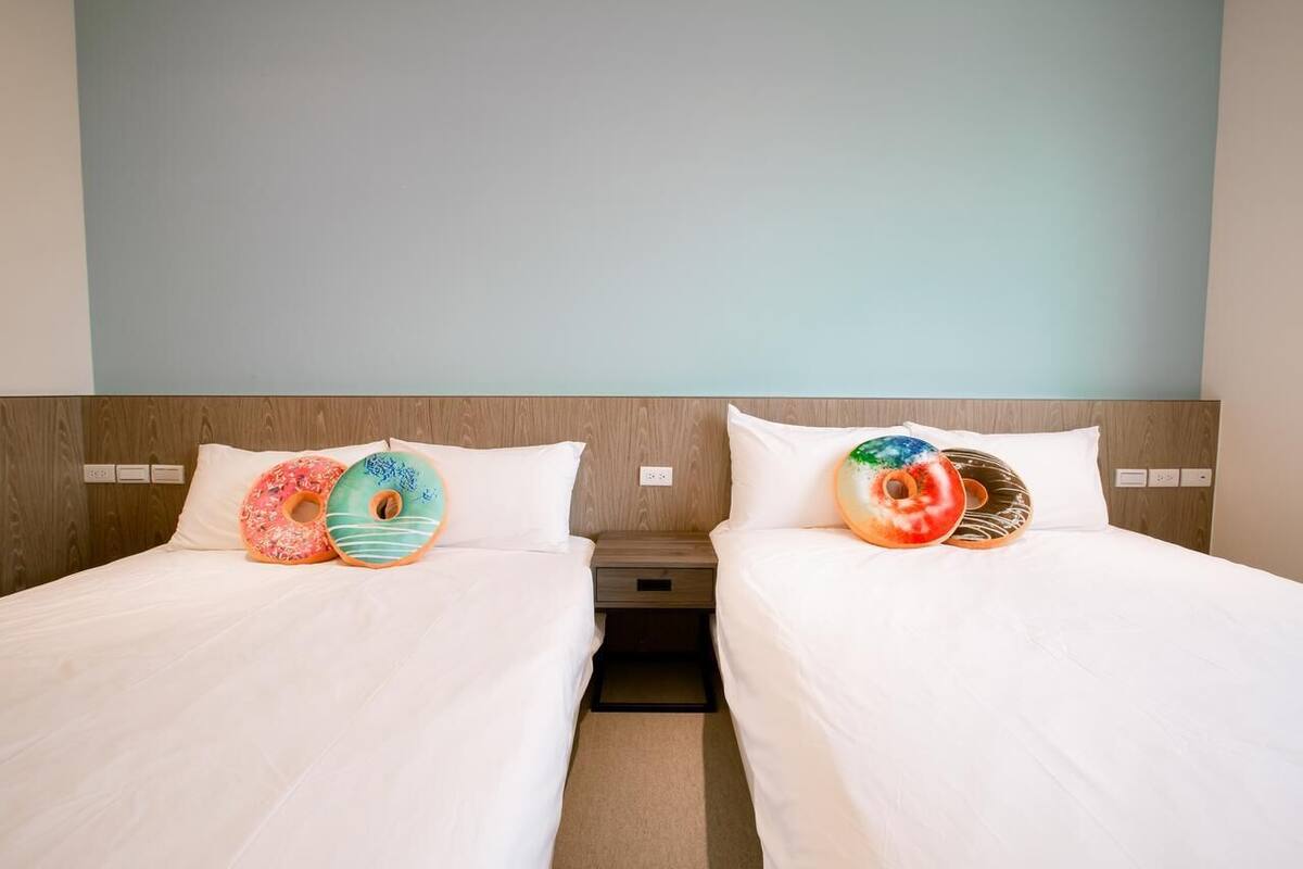 A hotel room with two beds, each with a pillow shaped like a donut.
