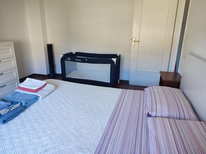 A bedroom with a bed, a changing table, a crib, and a dresser.