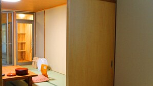 A traditional Japanese room with tatami flooring, a low wooden table with a red container, and a sliding door leading to a wooden shelf area. - Misasa Onsen Seiryusou (Misasa)