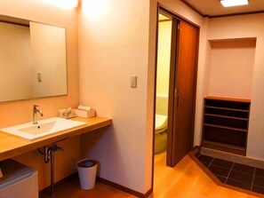 A bathroom with a wooden vanity, a sink, a mirror, and a toilet visible through an open door. - Misasa Onsen Seiryusou (Misasa)