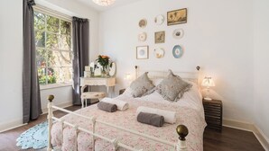 A bedroom with a bed, a dresser, a desk, and a window with curtains.
