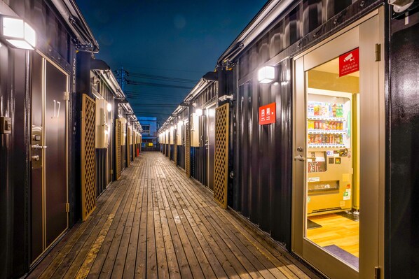 A corridor with doors leading to rooms, a vending machine, and a sign indicating a smoking area.