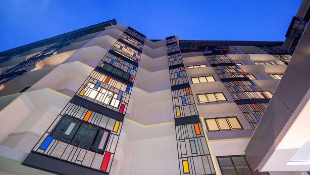 Ein modernes, mehrgeschossiges Gebäude mit einer geometrischen Fassade und zahlreichen Fenstern.