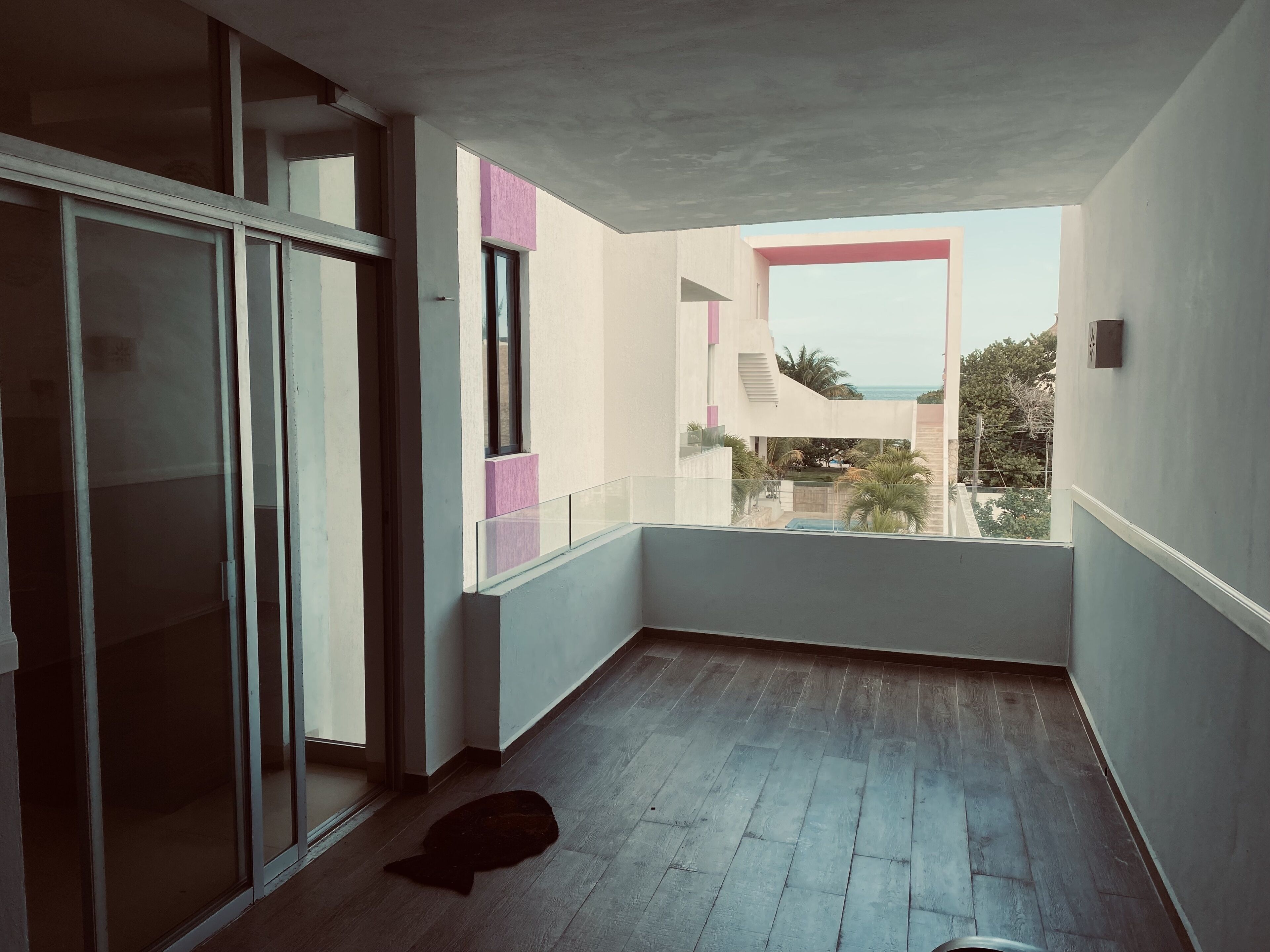 Een smal balkon met uitzicht op een gebouw en een palmboom.