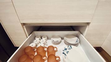 Un cajón con utensilios de cocina ordenados, incluyendo tazas, platos y tazones.