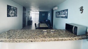 A modern kitchen with granite countertops, a microwave, and a dining area with a table and chairs. - AMA Yucatan (Progreso)
