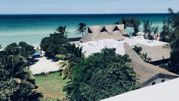 A resort with thatched-roof buildings, a pool, and a view of the ocean. - AMA Yucatan (Progreso)