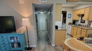 A modern kitchen with wooden cabinets, a dining table, and a TV in the living area. - The Place to Be !! Walk 2 Beach, Restaurants, Activities (St. Augustine)