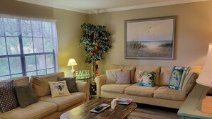 A cozy living room with two sofas, a coffee table, and a large window. - The Place to Be !! Walk 2 Beach, Restaurants, Activities (St. Augustine)