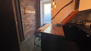 A kitchen with a wooden island, a brick wall, and a window. - Atypical village apartment (Olmeto)