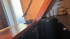 A kitchen with a wooden countertop, a small refrigerator, and a window with a view of the outside. - Atypical village apartment (Olmeto)