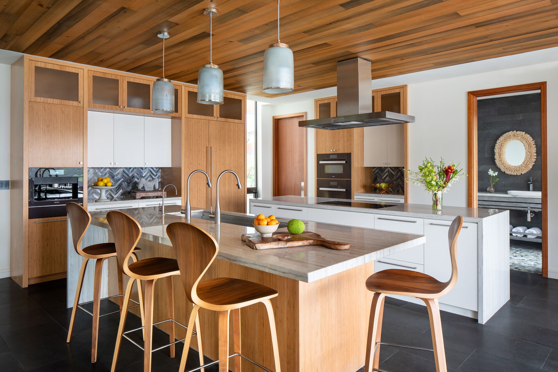 A modern kitchen with wooden cabinets, stainless steel appliances, and a central island with bar stools.