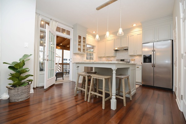 Fully-stocked kitchen has room for 4 at a granite island and a table nearby.