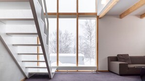 Un interno moderno con una scala, un divano e un'ampia finestra che offre vista sull'esterno.