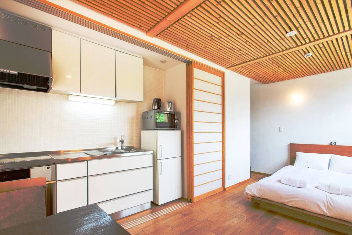 Ein kleines Zimmer mit einer Küchenzeile, einem Bett und einer Holzbalkendecke.