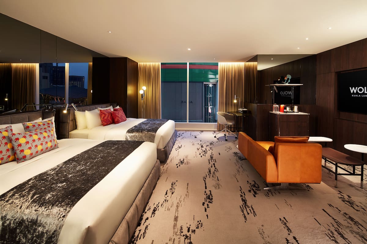 A modern hotel room with a large bed, a sofa, a small table, and a TV.