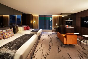 Une chambre d’hôtel moderne avec un grand lit, un canapé, une petite table et un téléviseur.