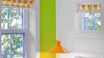 Ein Zimmer mit einer weißen Couch, einer grünen Wand und einem Fenster mit orangefarbenen Vorhängen.