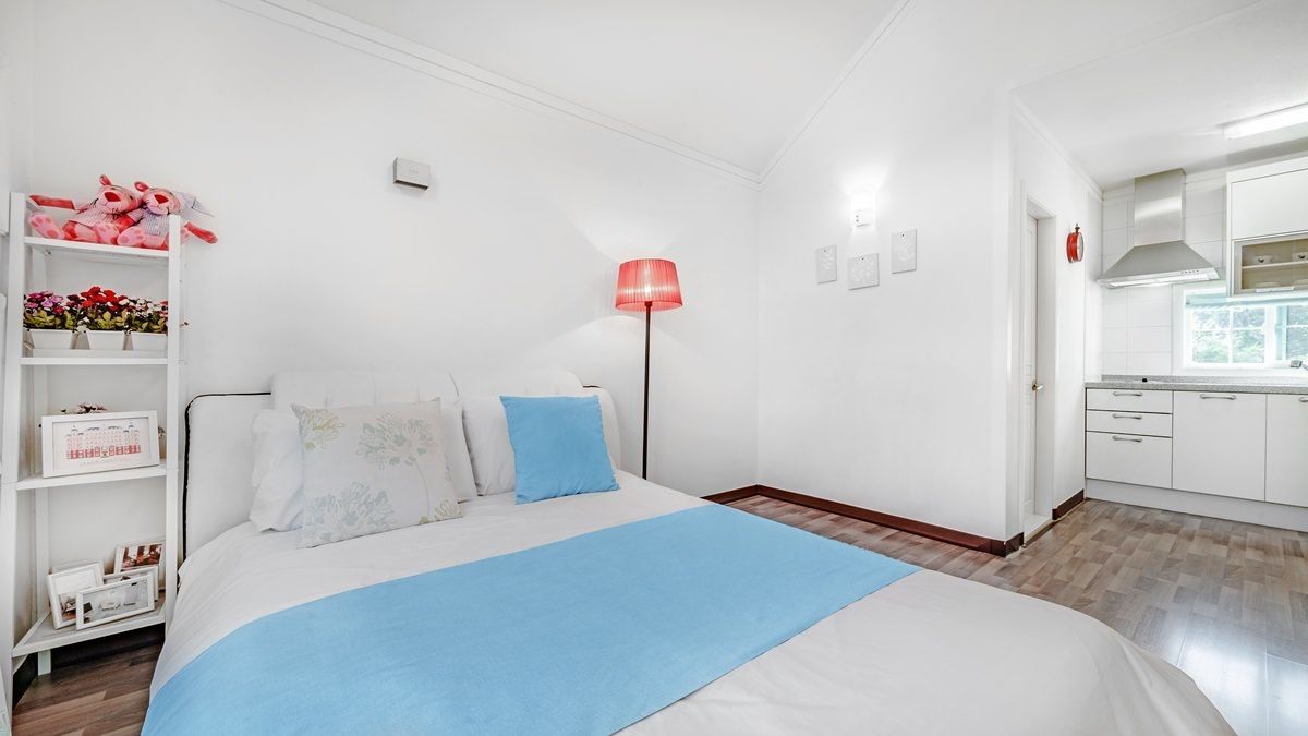 Una camera da letto con un letto, un comodino, una lampada e vista sulla cucina.