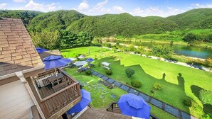 A view of a hotel with a deck, outdoor seating, and a river in the background. - Star Sonata Pension (Hongcheon)