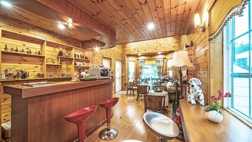 Interior acogedor de una cabaña de madera con zona de bar, comedor y un amplio ventanal con vistas.
