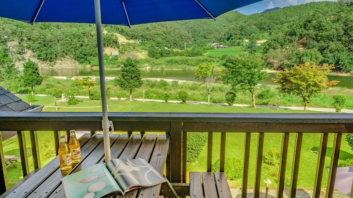 A wooden deck with a view of a river and hills.