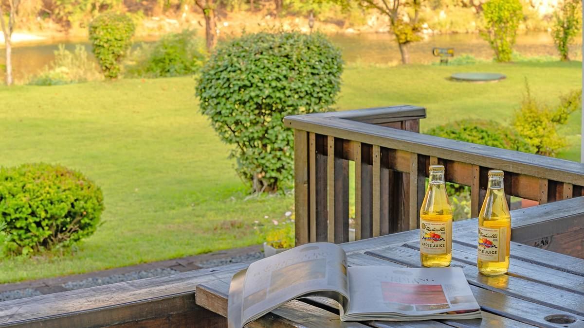 A wooden deck with a magazine and two bottles of apple juice.