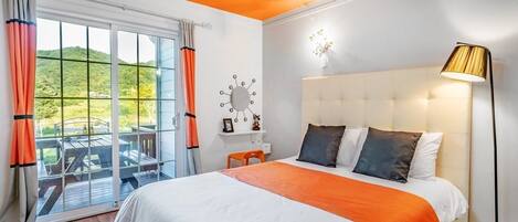 A bedroom with a large bed, a nightstand, a lamp, and a view of the outdoors through a sliding glass door.