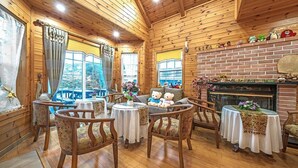 A cozy wooden cabin interior with a fireplace, a sofa with plush toys, and a dining area with round tables and chairs. - Star Sonata Pension (Hongcheon)
