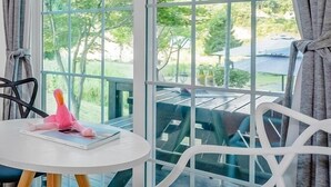 A room with a large window, a white chair, a small round table, and a hanging light fixture. - Star Sonata Pension (Hongcheon)