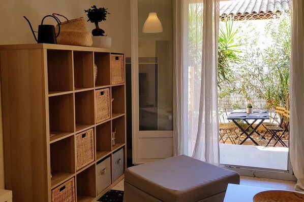 A room with a wooden bookshelf, a cushioned bench, and a table outside.